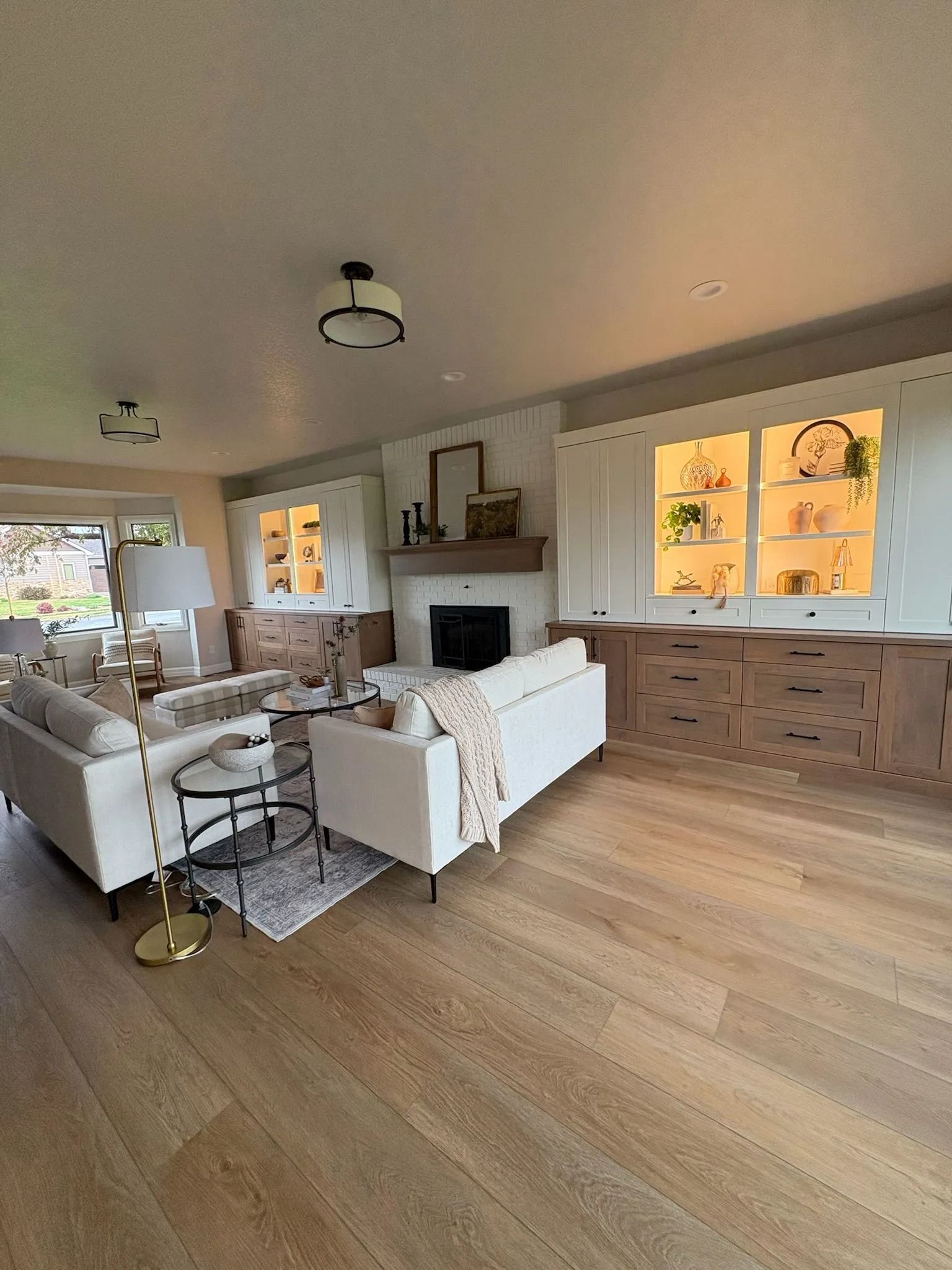 Living room with white sofas, fireplace, built-in cabinets with illuminated display shelves, and hardwood floors.