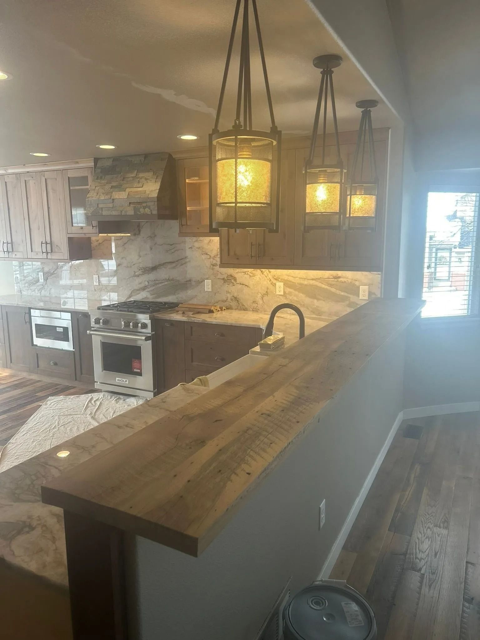 Kitchen with granite countertops, wooden cabinets, and hanging pendant lights over a countertop bar.