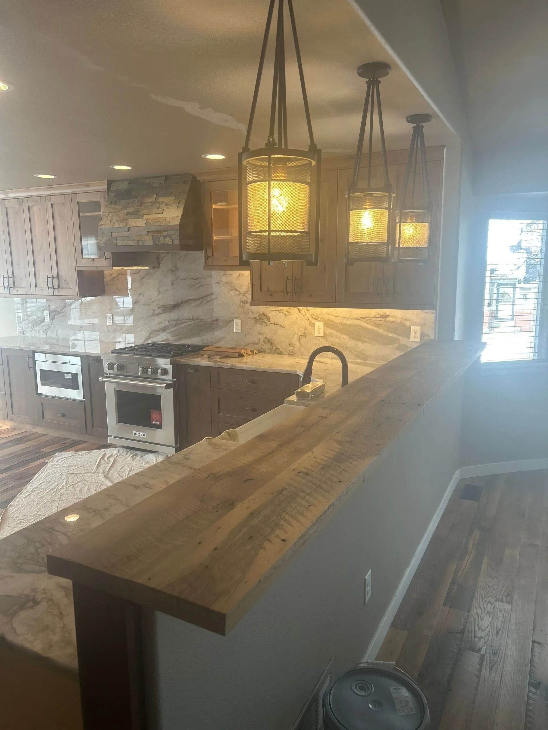 Kitchen with granite countertops, wooden cabinets, and hanging lanterns.