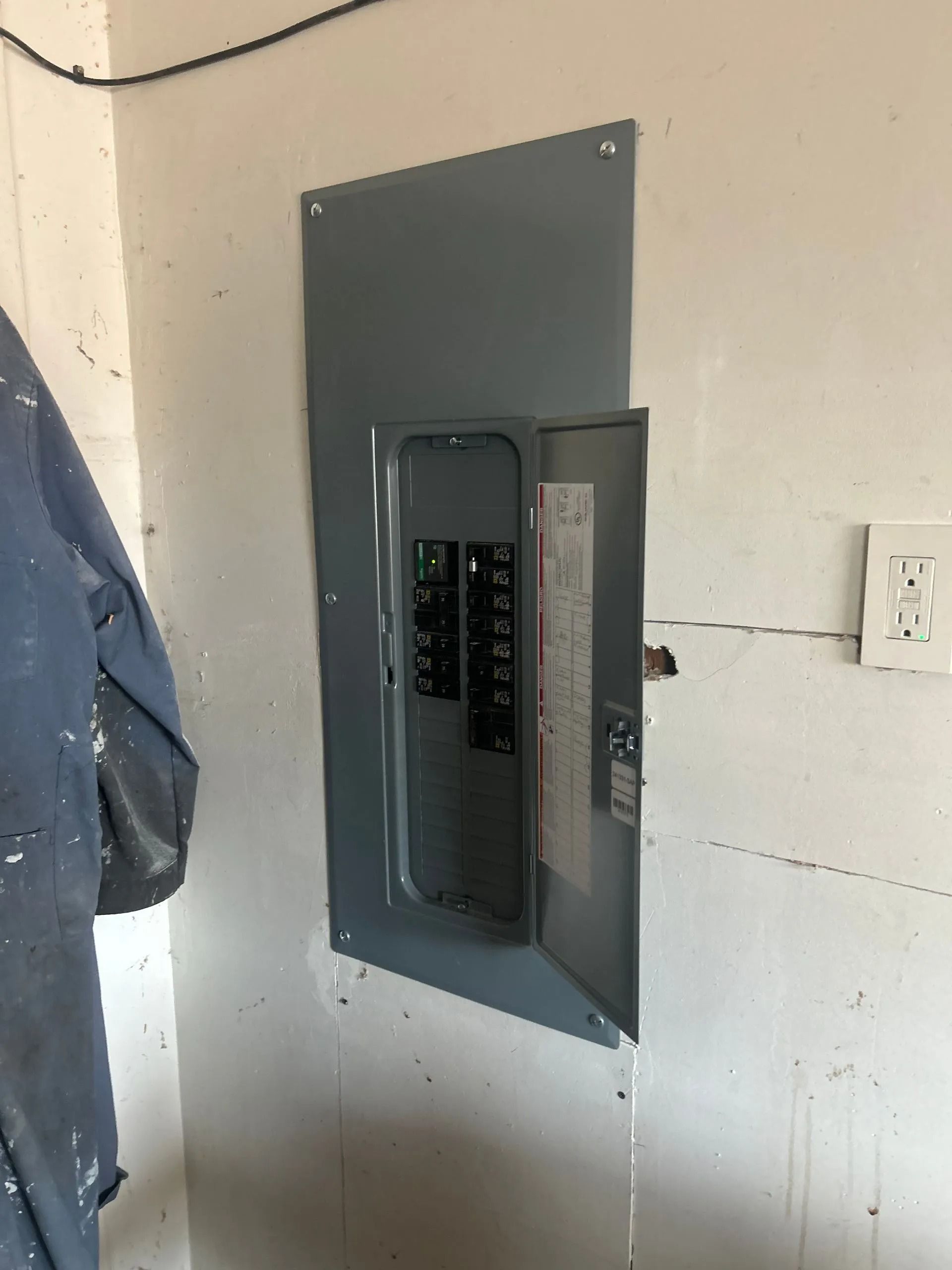 Electrical panel on a white wall, door open showing circuit breakers.