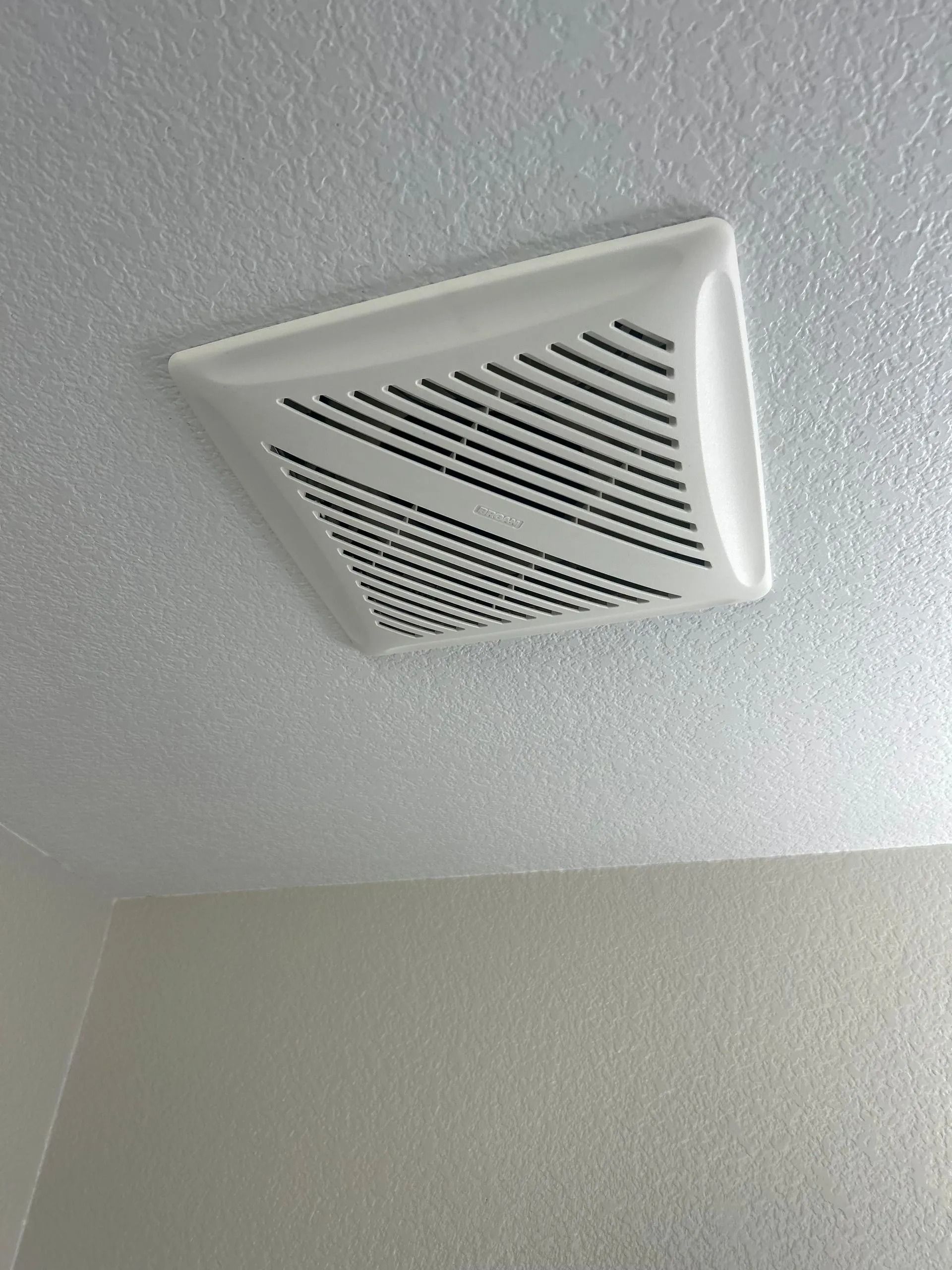 White bathroom exhaust fan on textured ceiling.