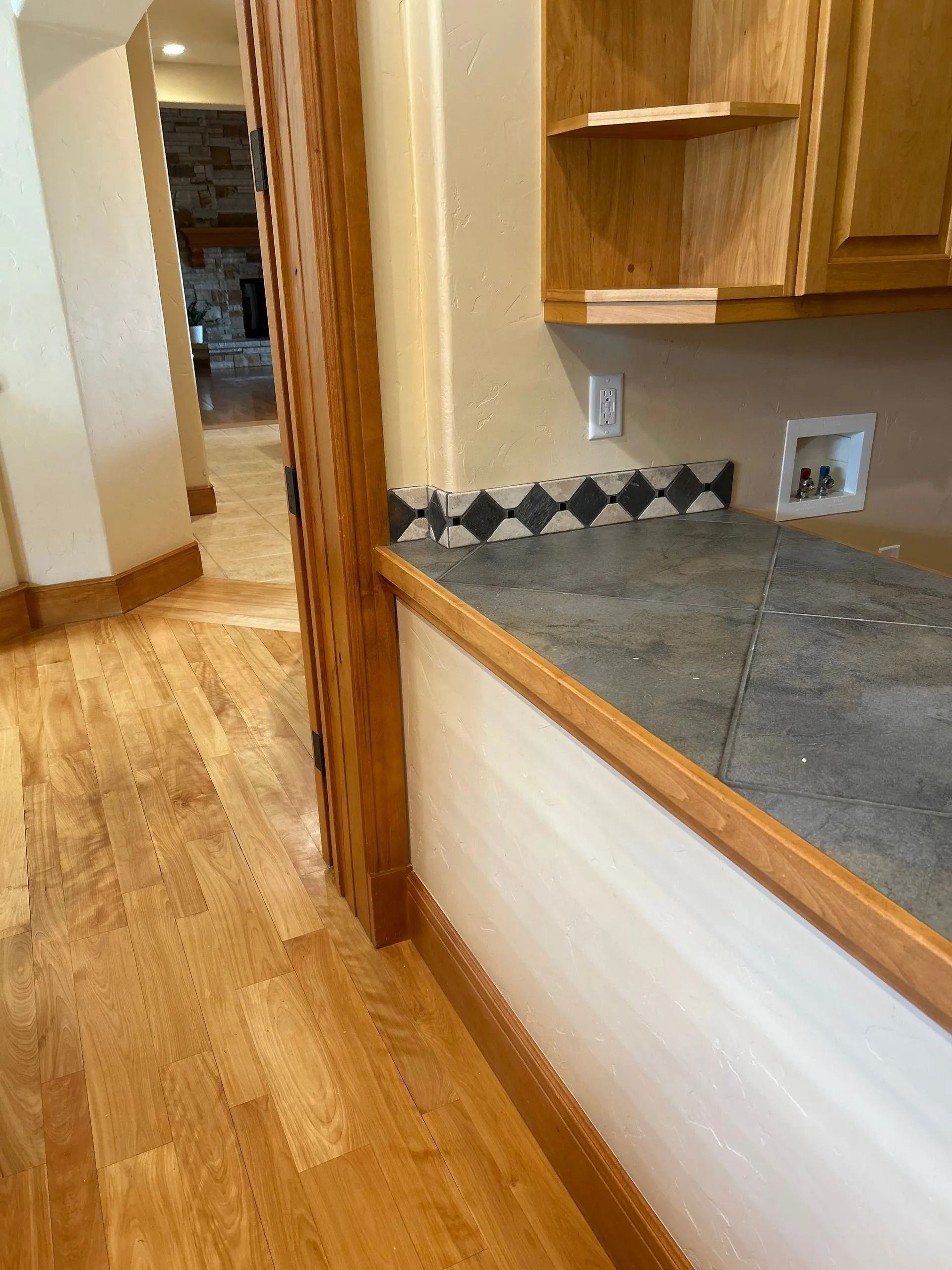 Kitchen counter with wood trim and backsplash, adjacent to hardwood floor and cabinets.