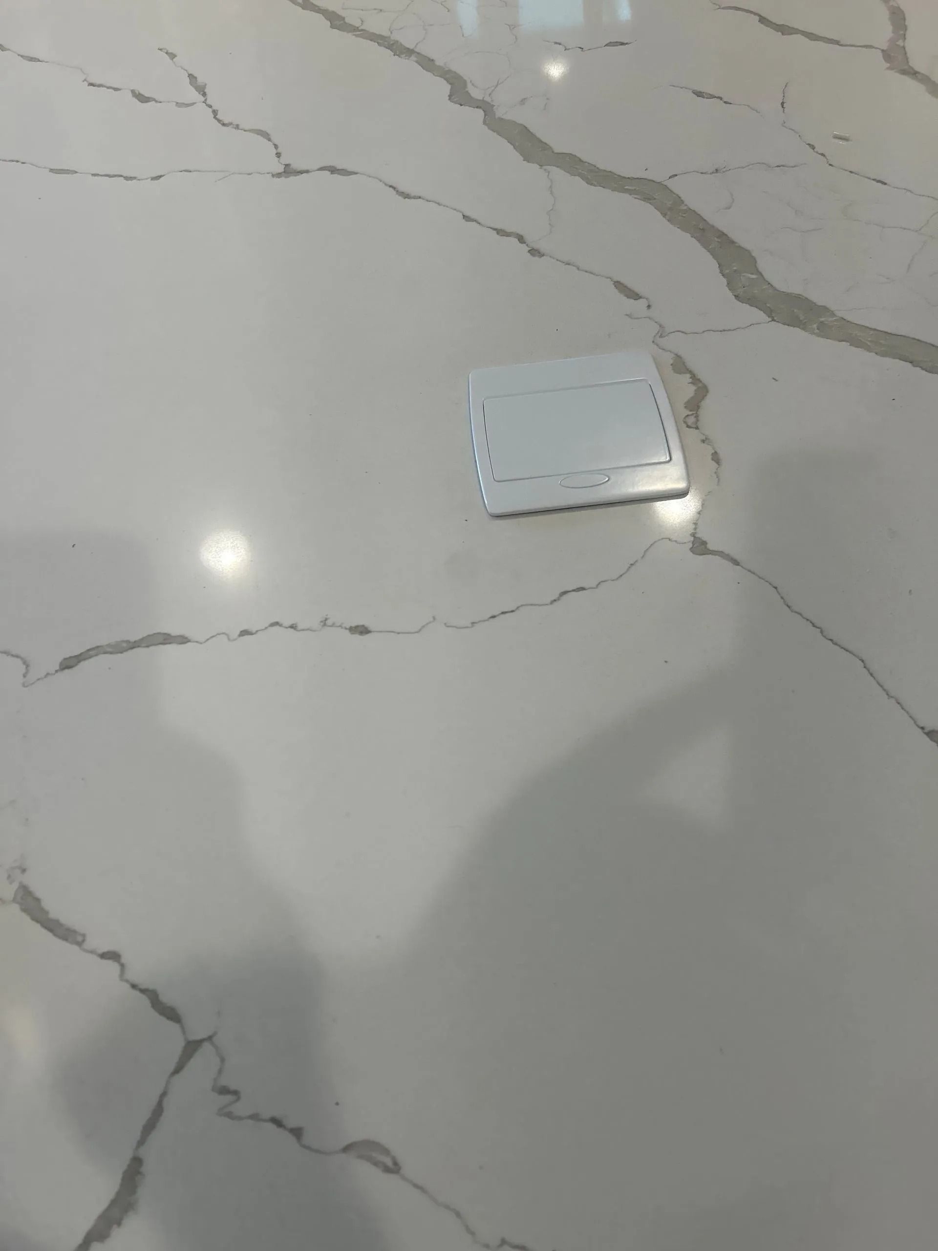 White countertop with gray veining and a light-colored electrical outlet cover.
