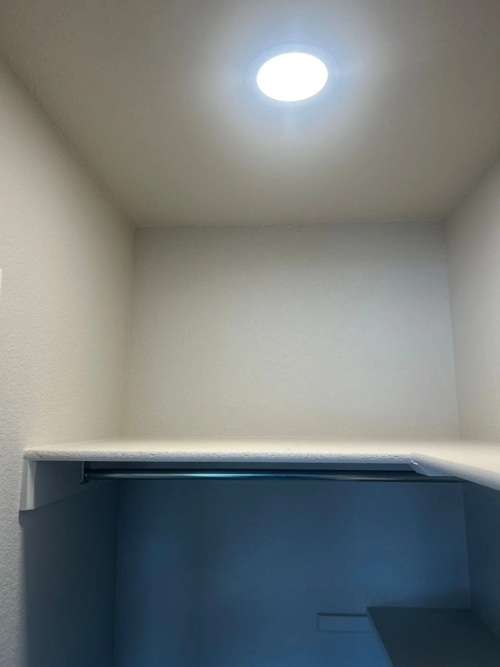 Empty closet with shelf, hanging rod, and ceiling light.