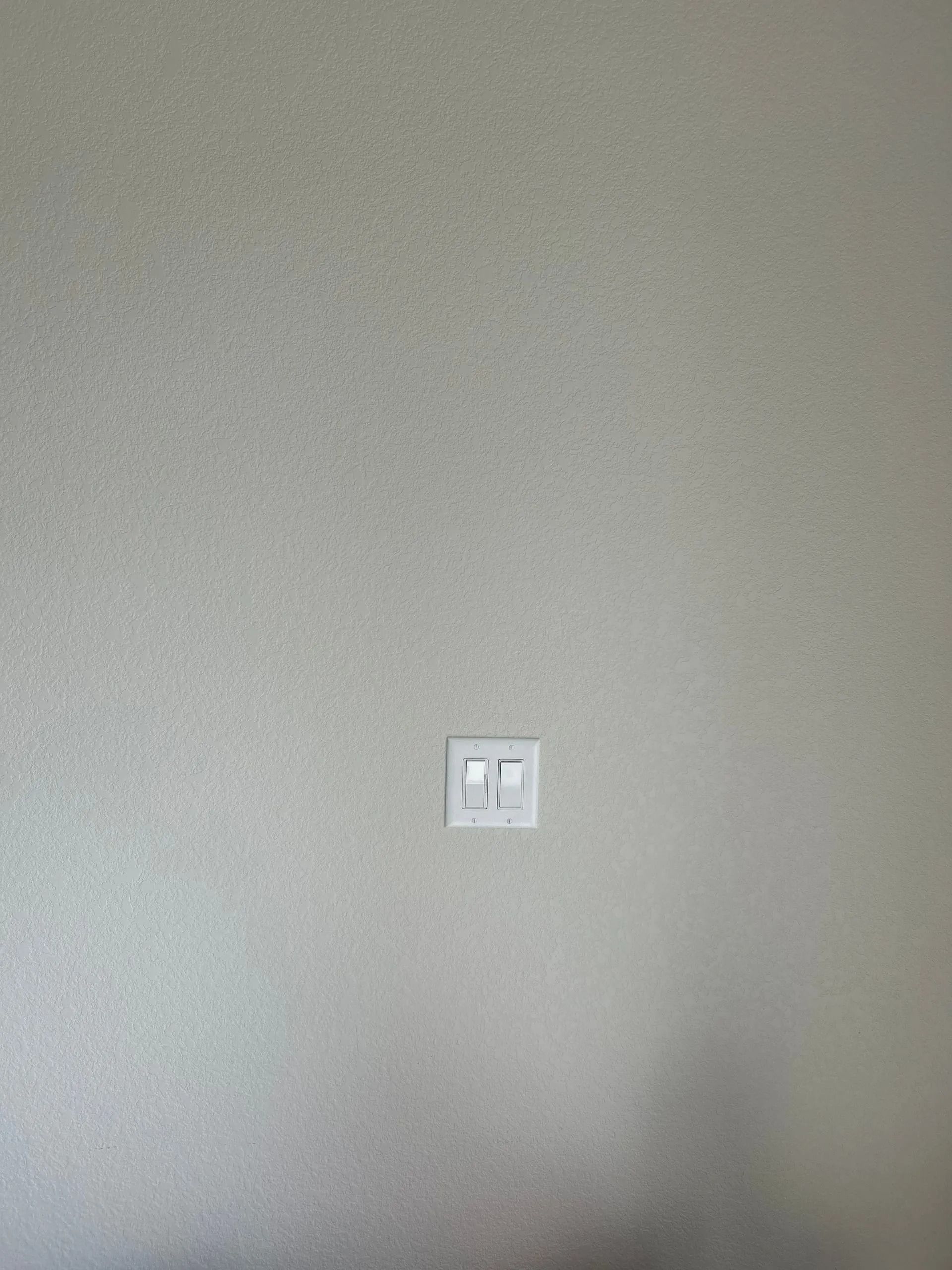 White wall with two light switches in the center.