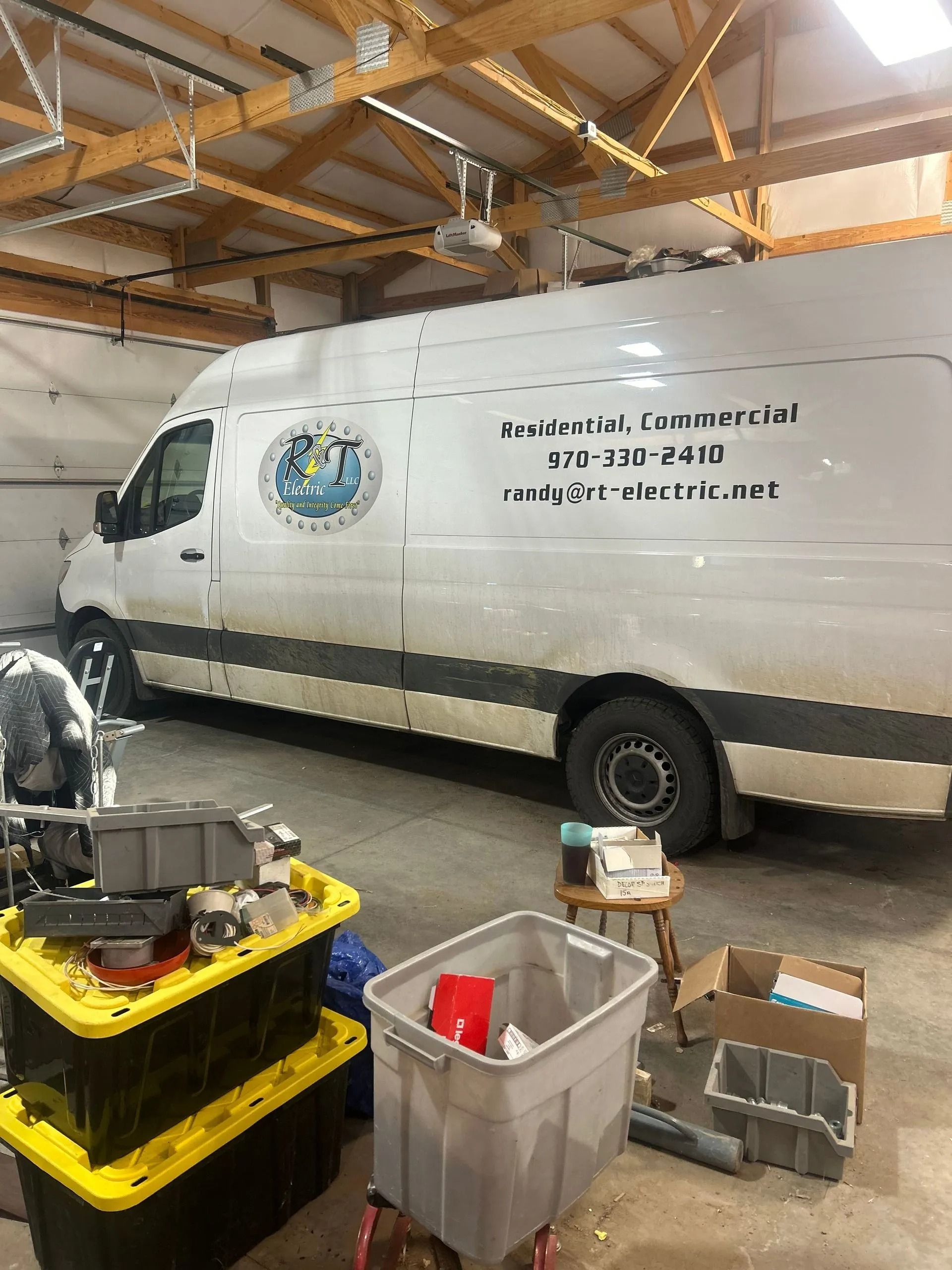 White van in a garage with company logo, tools, and storage bins.