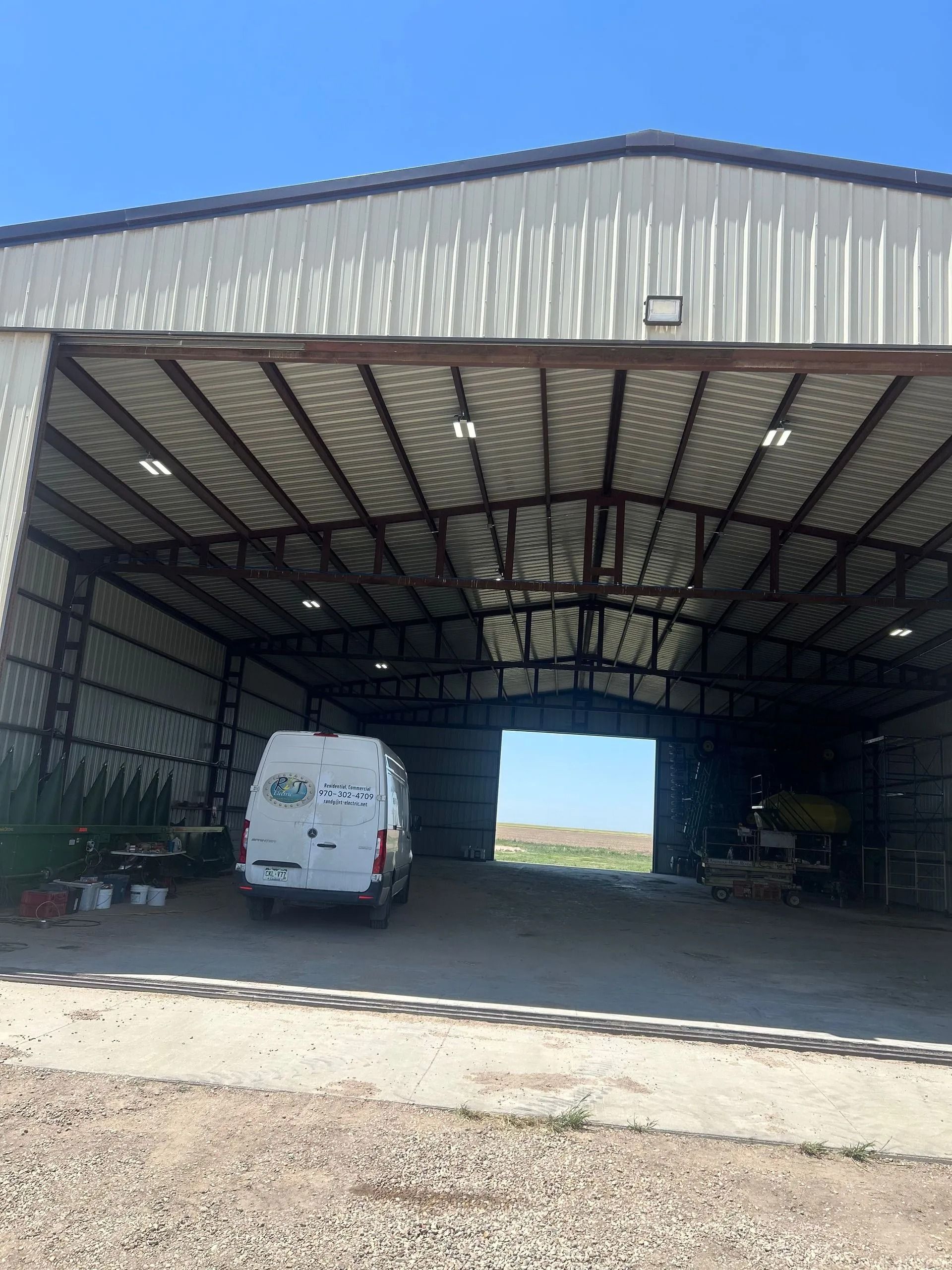 White van inside an open metal building, blue sky visible beyond the opening.