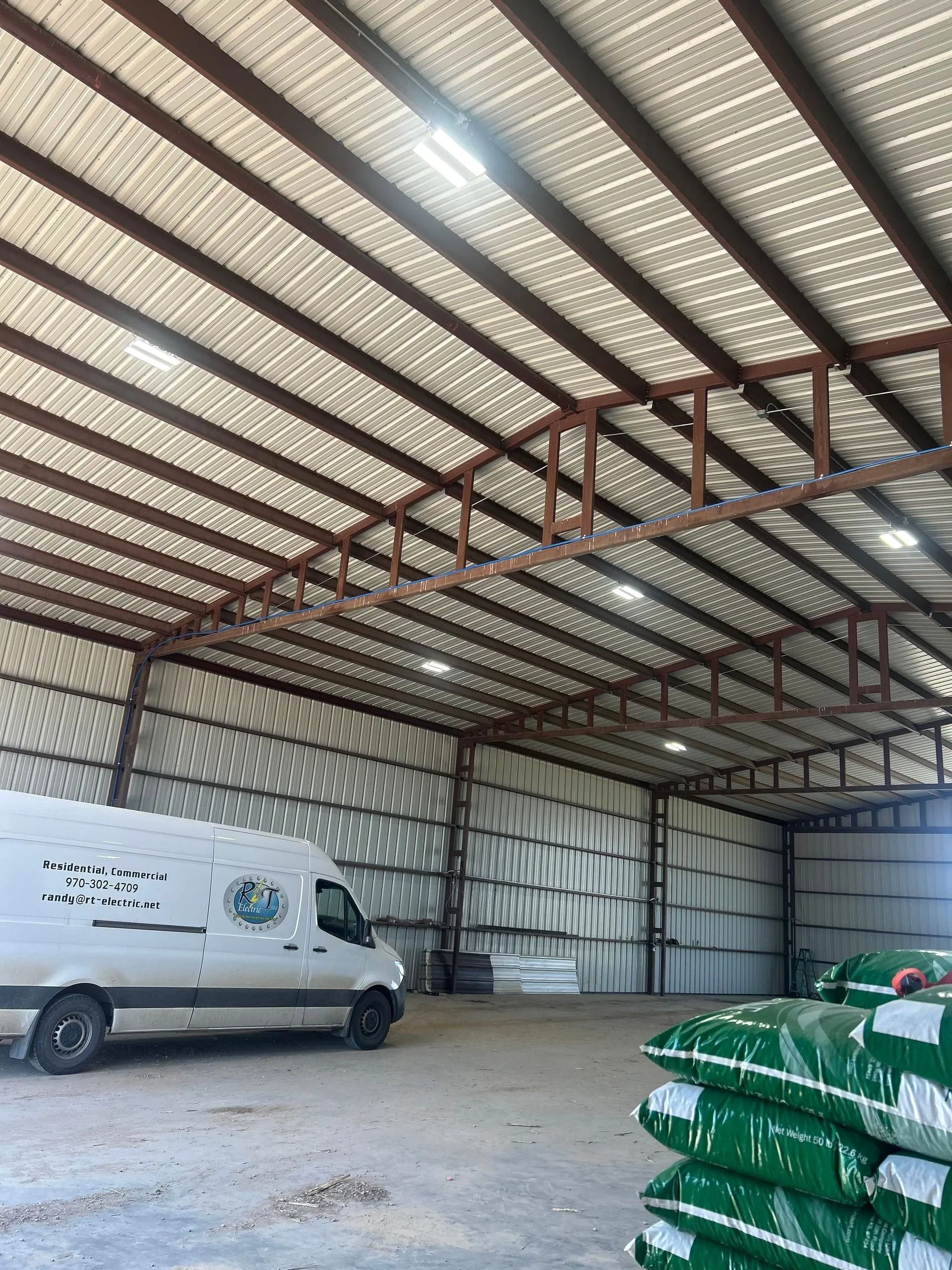 Interior of a metal warehouse with a white van and stacks of green bags.