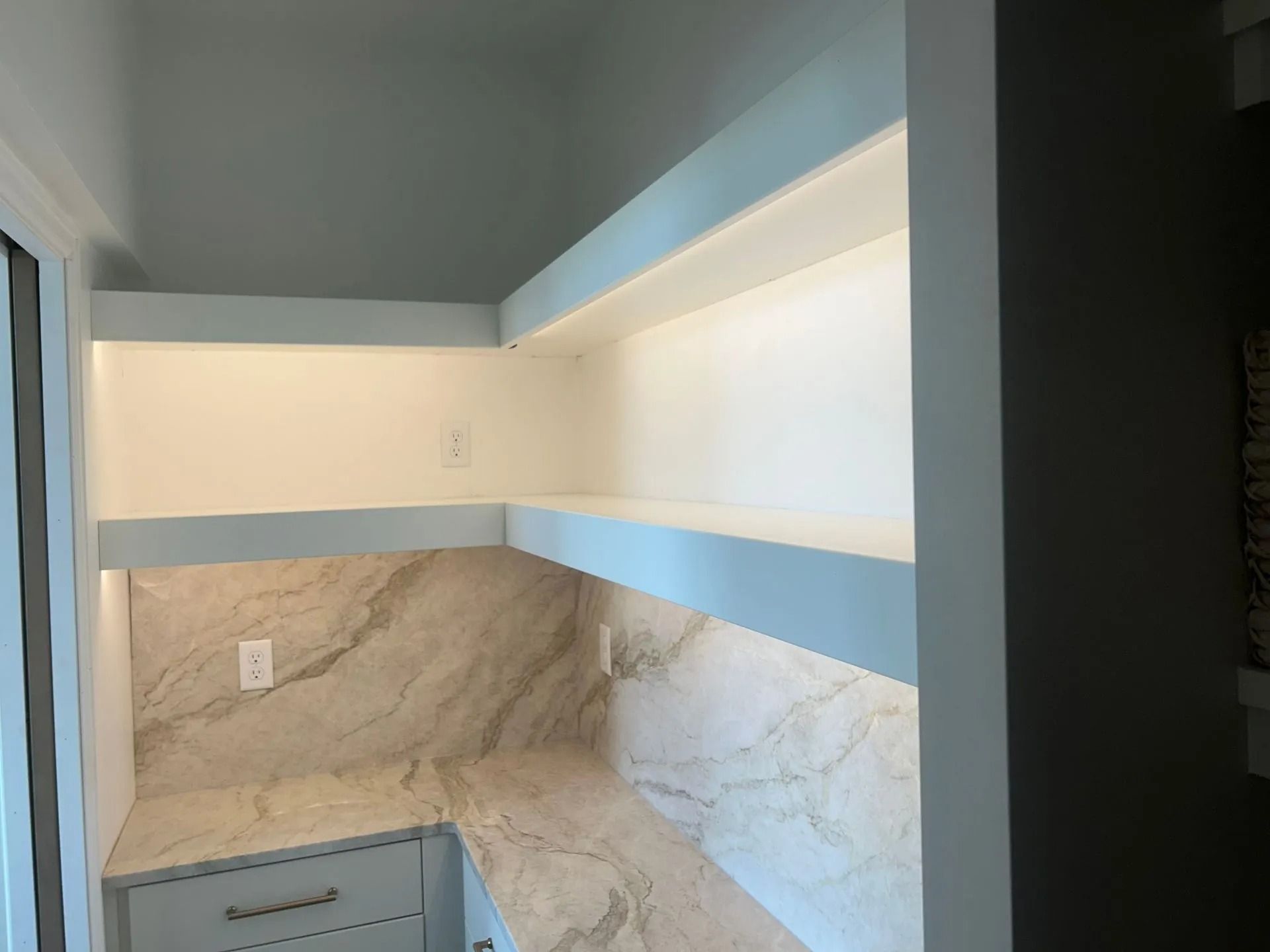 Built-in shelves with countertop, illuminated by LED lights. Interior design with neutral tones.