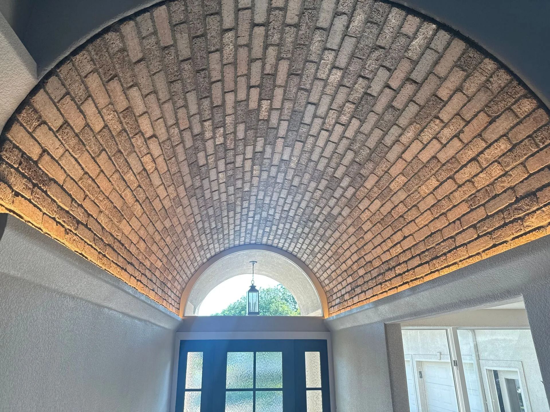 Brick arched ceiling with warm lighting above a doorway.