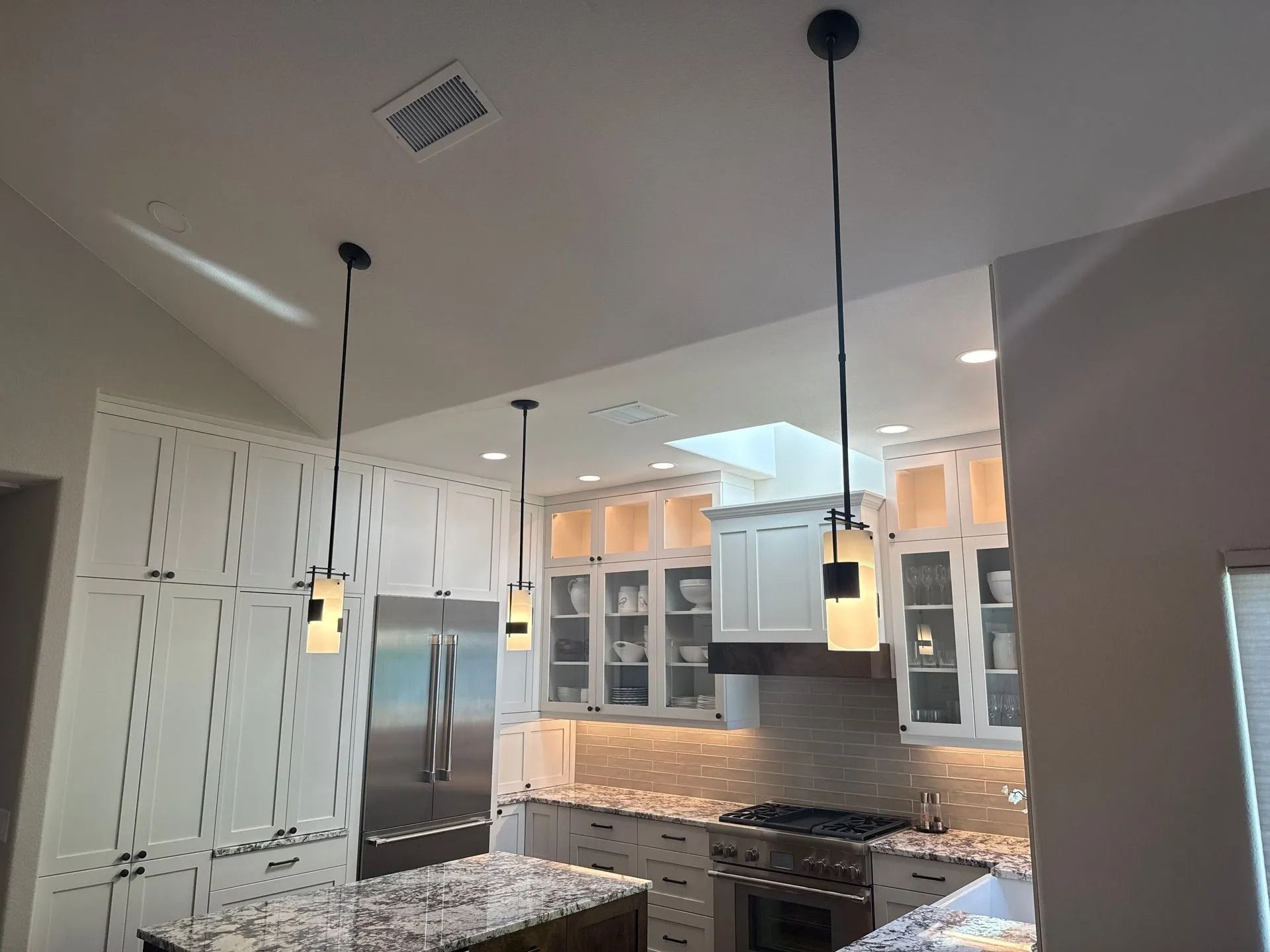 Kitchen with white cabinets, stainless steel appliances, and pendant lights.