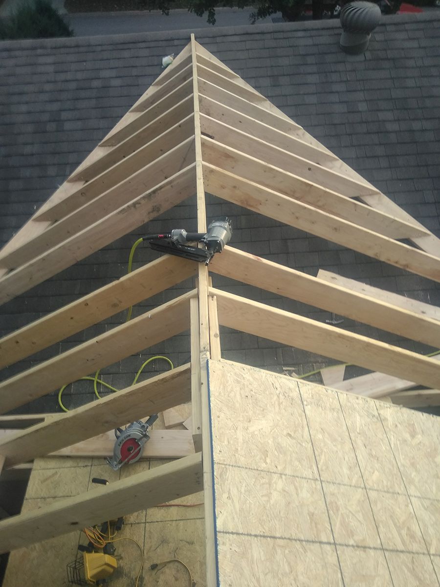 A wooden structure is being built on top of a roof.