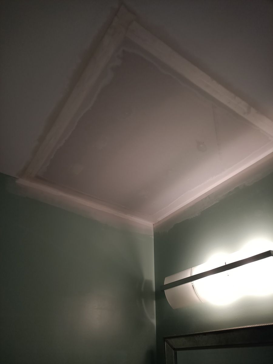 A bathroom with a light on the wall and a ceiling.