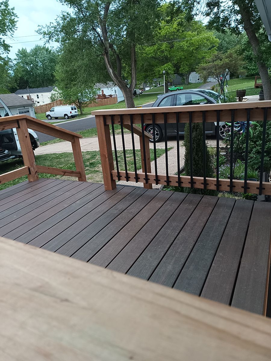 A wooden deck with a metal railing and stairs leading up to it.