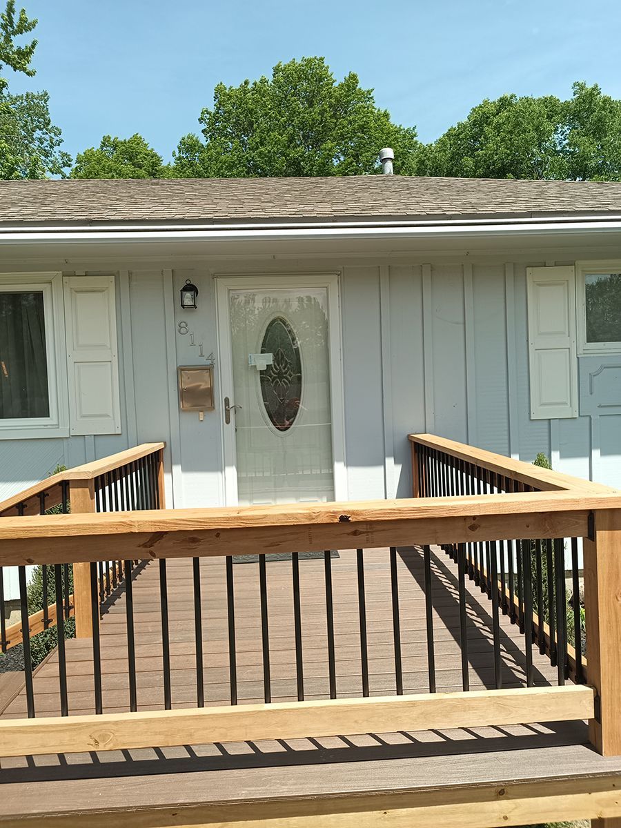 A house with a wooden deck leading to the front door.