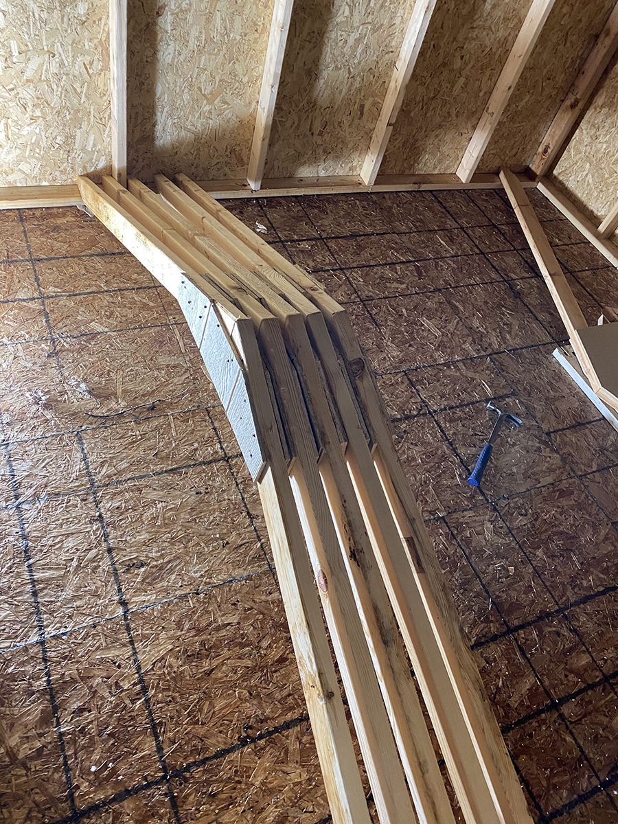 A bunch of wooden boards are stacked on top of each other on a tiled floor.