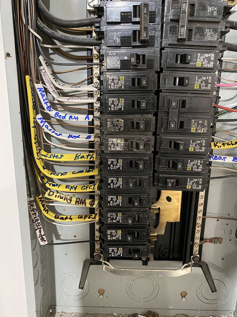 A close up of a electrical panel with a lot of wires coming out of it.