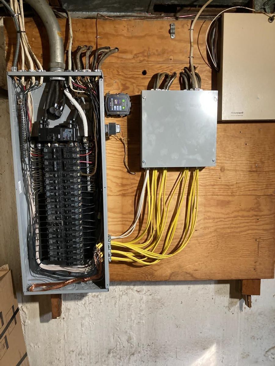 A electrical box with a bunch of wires coming out of it is on a wooden wall.