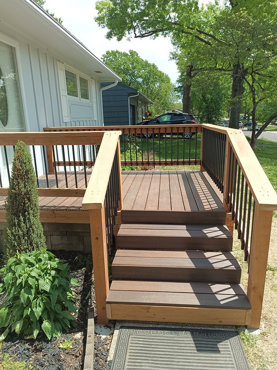 A wooden deck with stairs leading up to it is in front of a house.