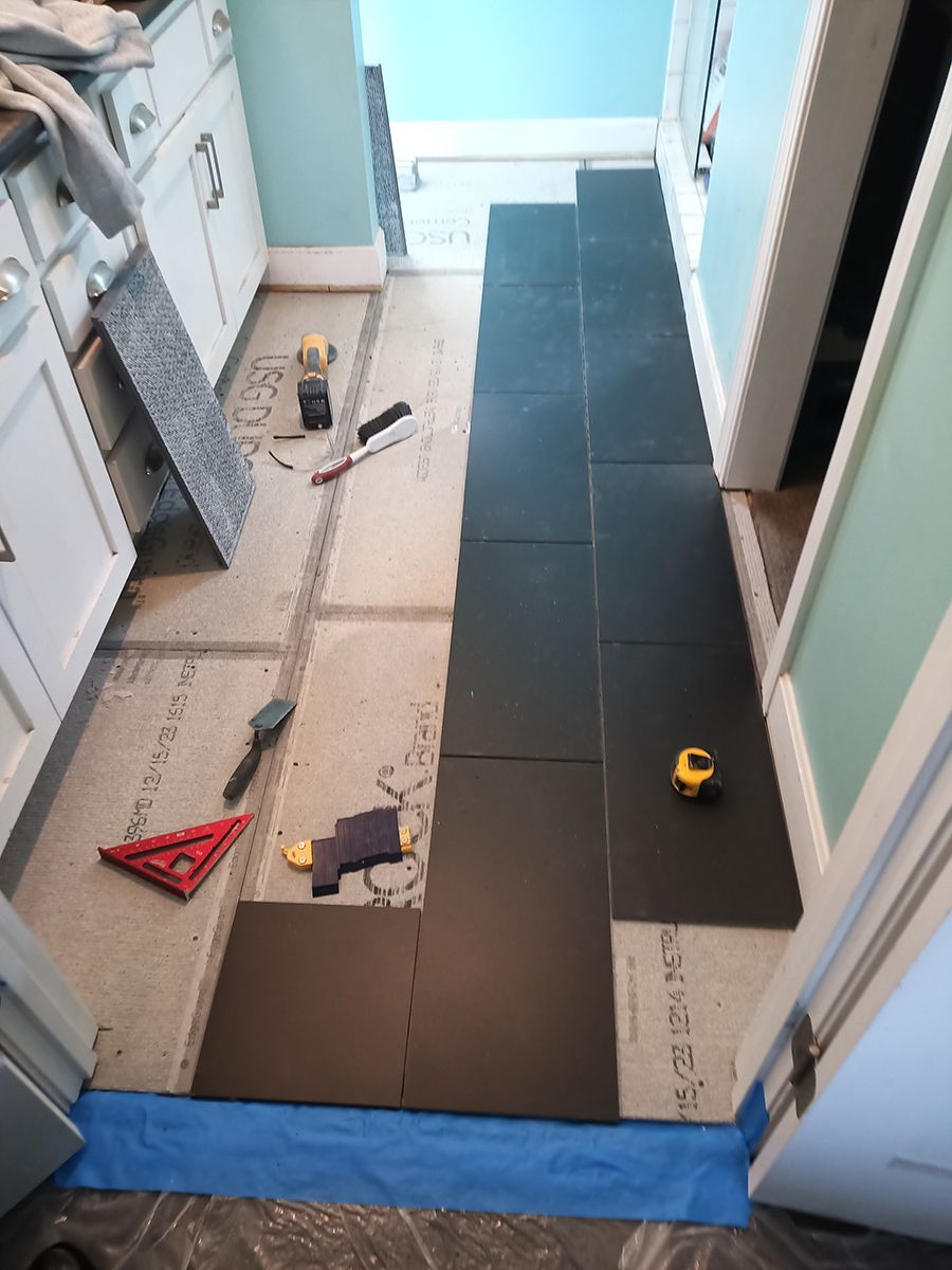 A bathroom floor is being tiled with black tiles.