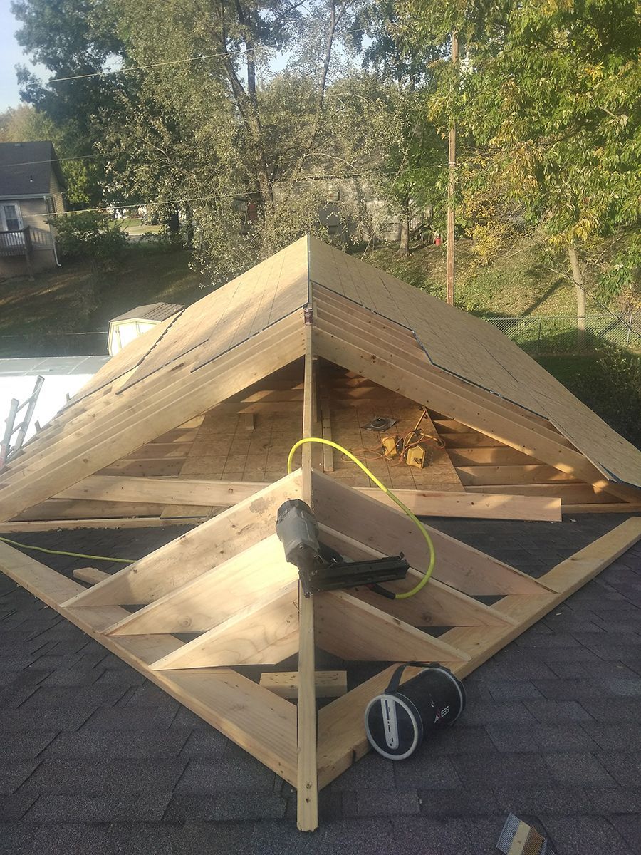 A wooden structure is being built on top of a roof.