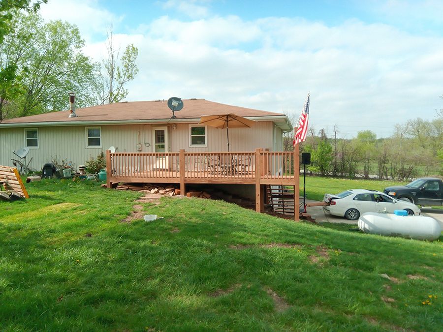 A house with a large deck and a satellite dish on the roof.