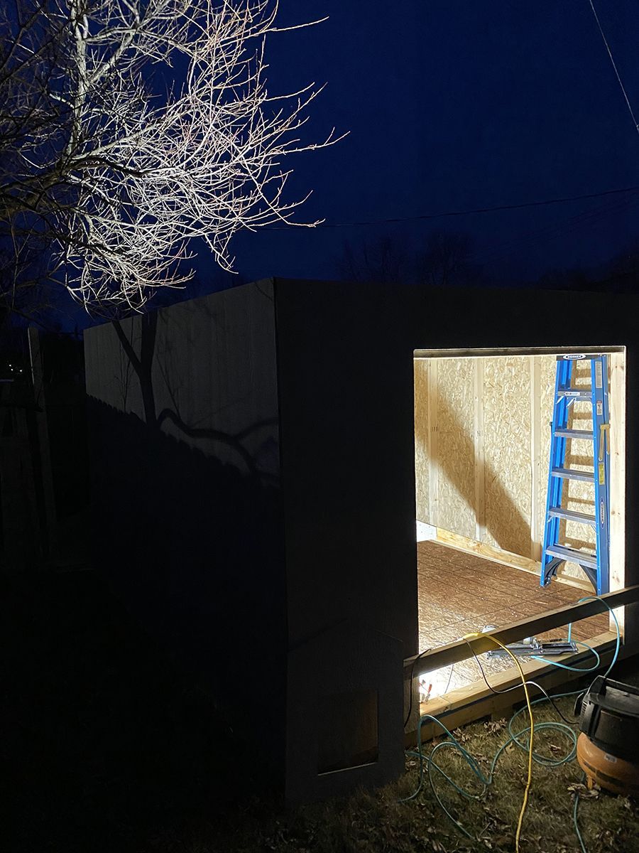 A ladder is sitting in the doorway of a garage at night.