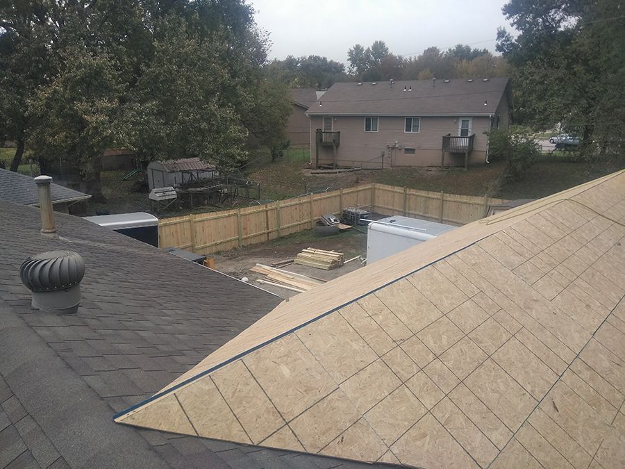 An aerial view of a roof with a fence and a house in the background.