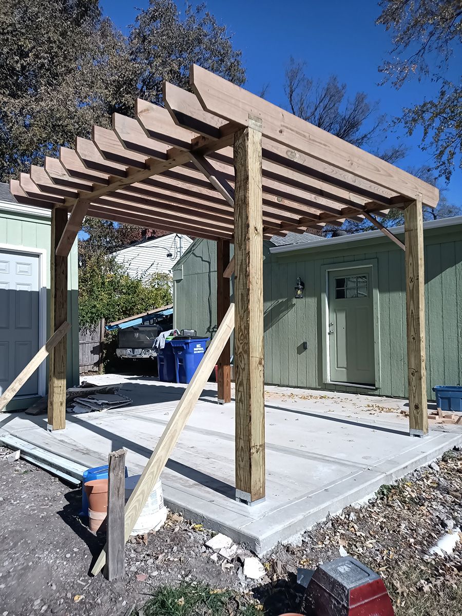 A wooden pergola is being built in front of a house.