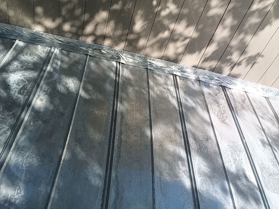 A close up of a metal roof with a wooden deck in the background.