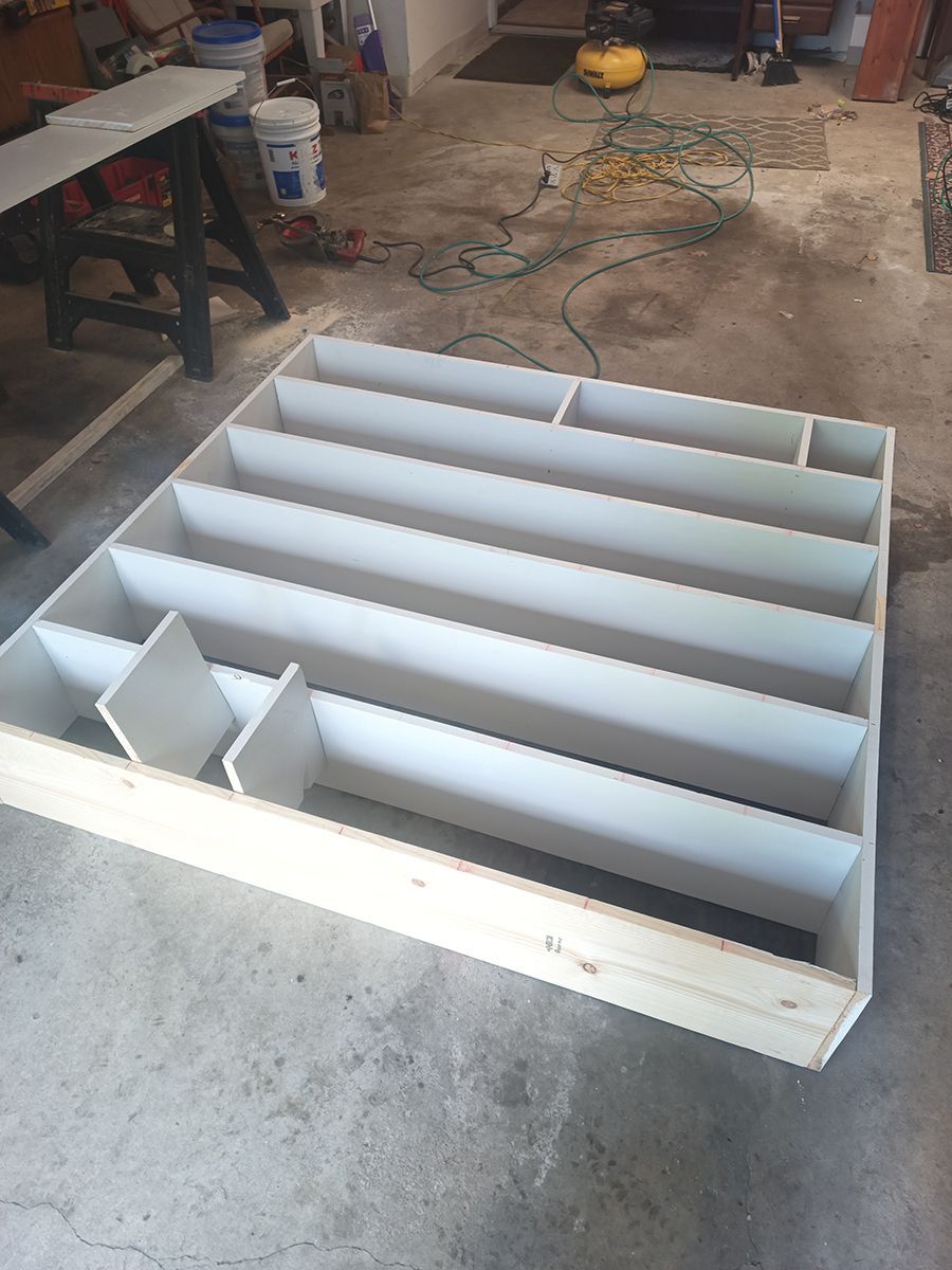 A wooden shelf is sitting on the floor in a garage.