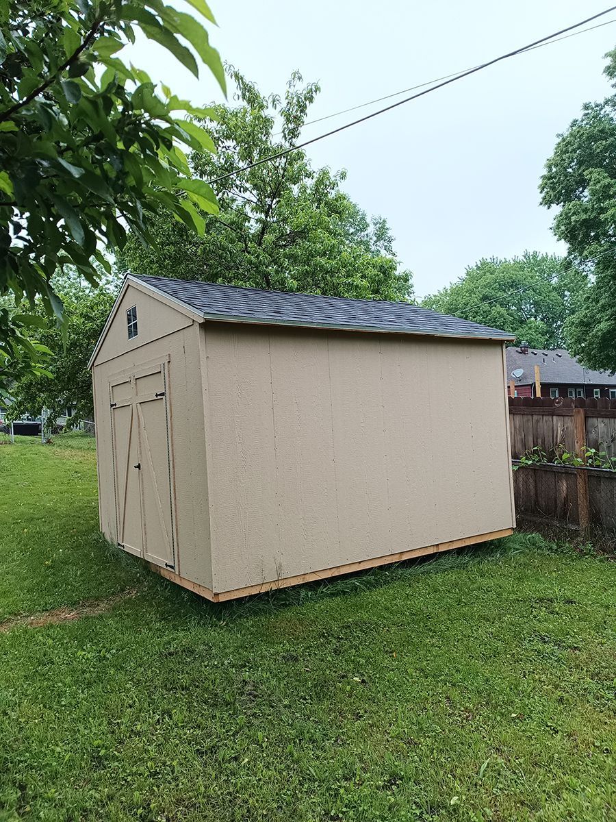 A small shed is sitting in the middle of a lush green field.