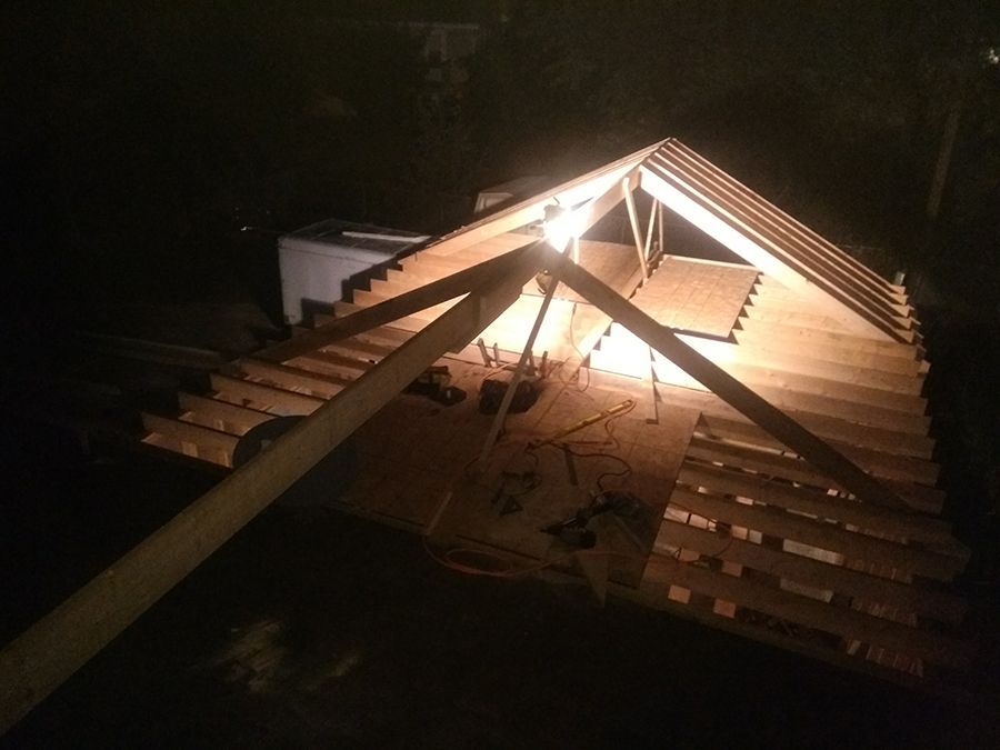 The roof of a building is being built at night.