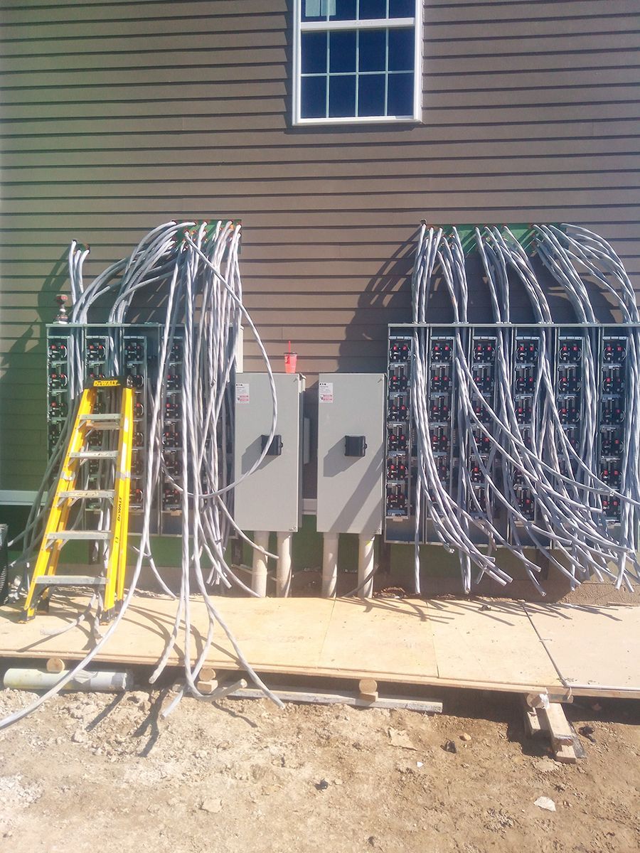 A ladder is sitting next to a bunch of wires on the side of a building.
