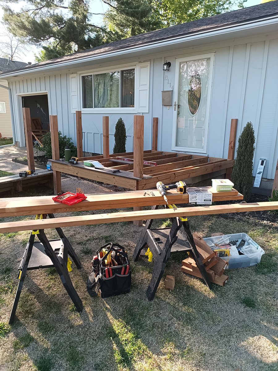 A wooden deck is being built in front of a house.