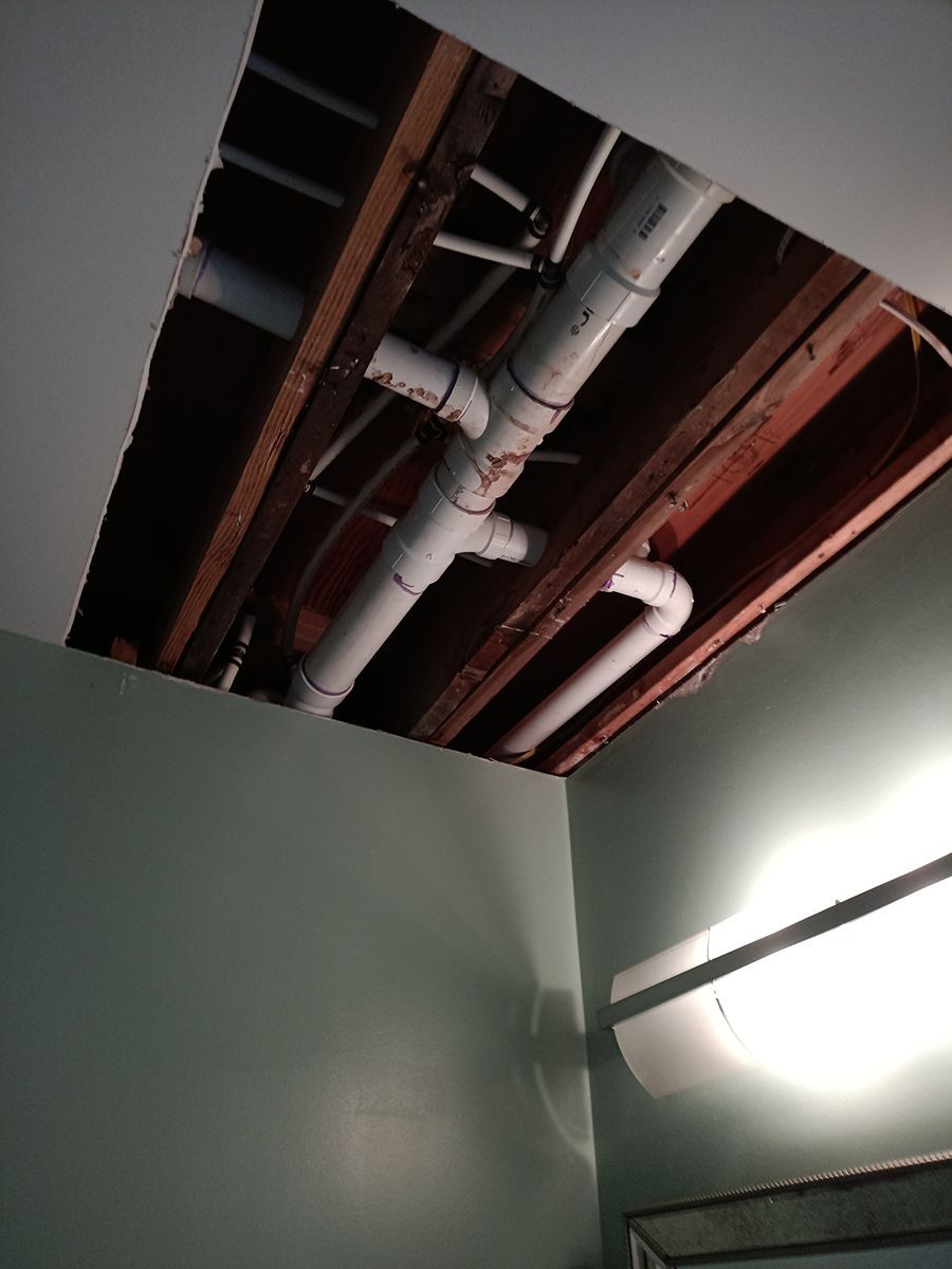 A room with a hole in the ceiling and pipes coming out of it.