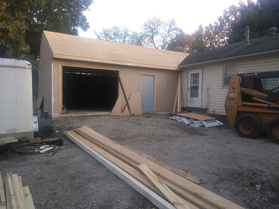 A tractor is parked in front of a garage under construction.