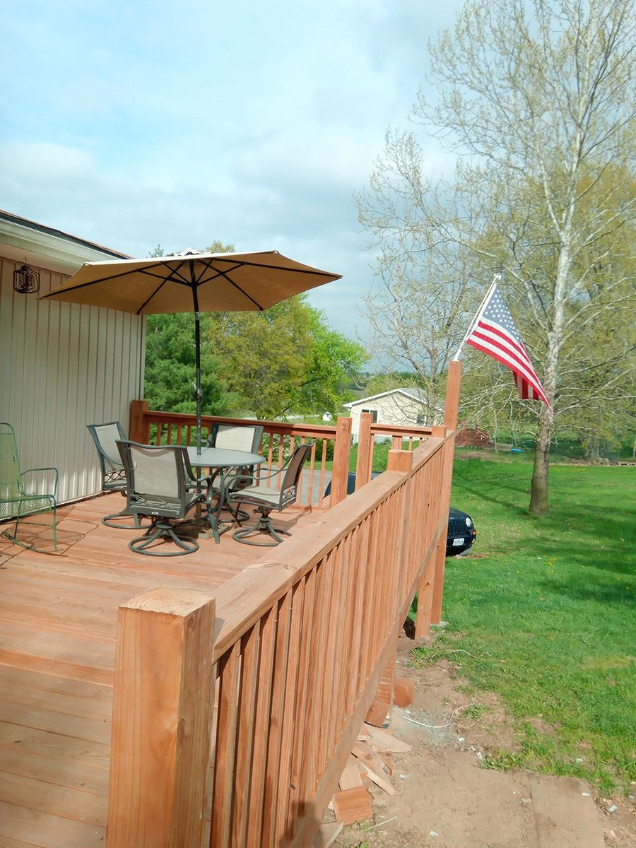 A wooden deck with a table and chairs and an American flag.