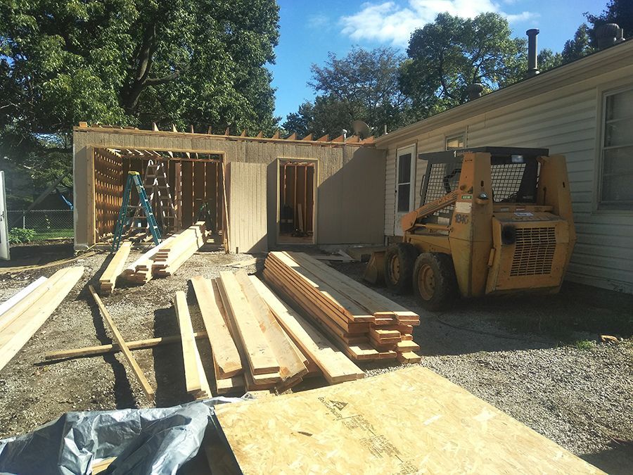 A skid steer is parked in front of a house under construction.