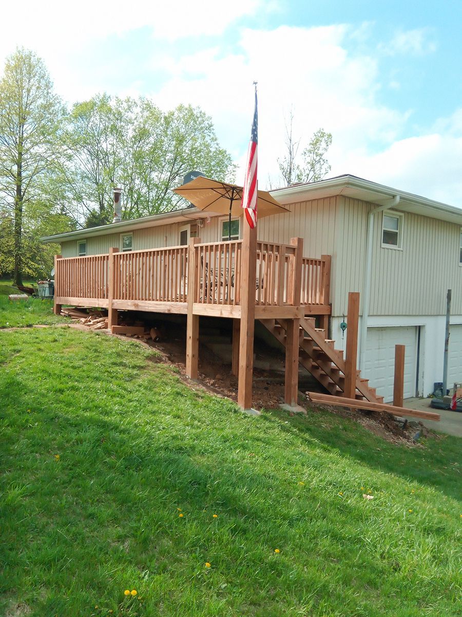 A house with a wooden deck and stairs in front of it.