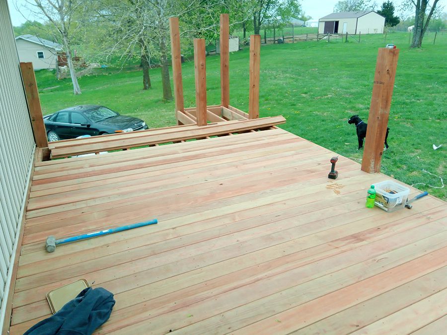 A wooden deck is being built with a dog in the background.