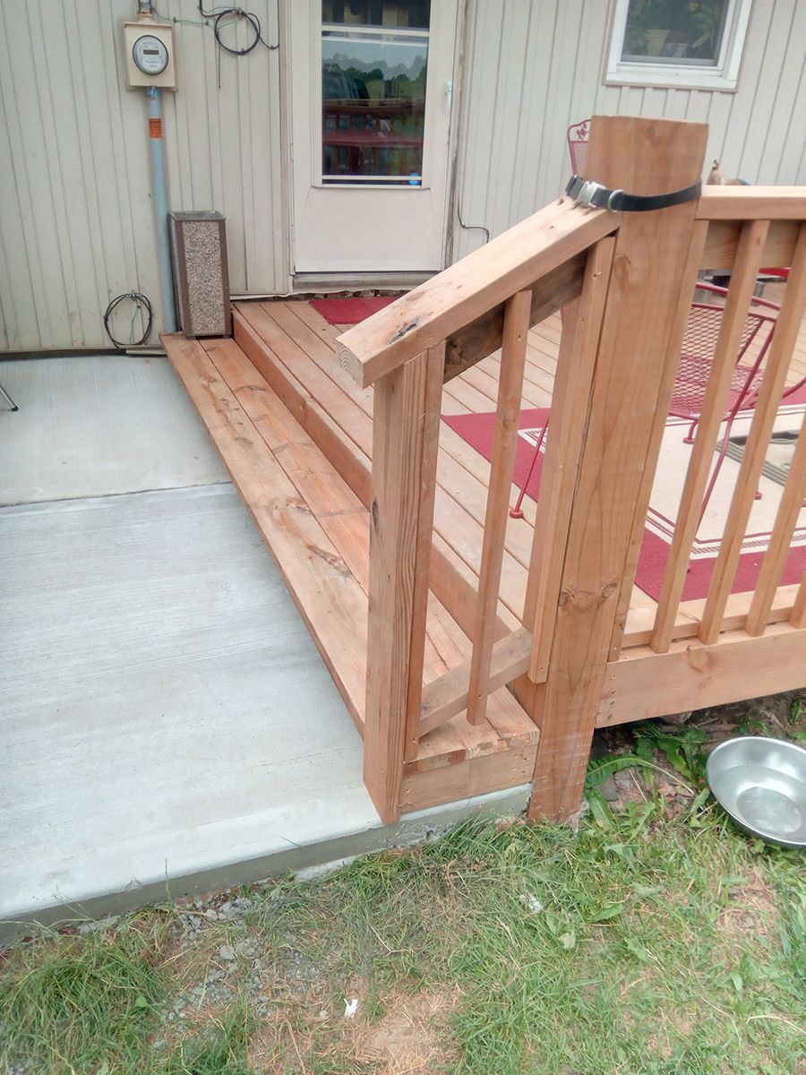 A wooden deck with stairs leading up to a house.