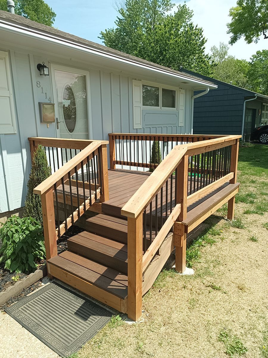 A wooden deck with stairs leading up to it is in front of a house.