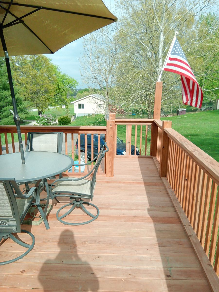 A wooden deck with a table and chairs and an American flag.