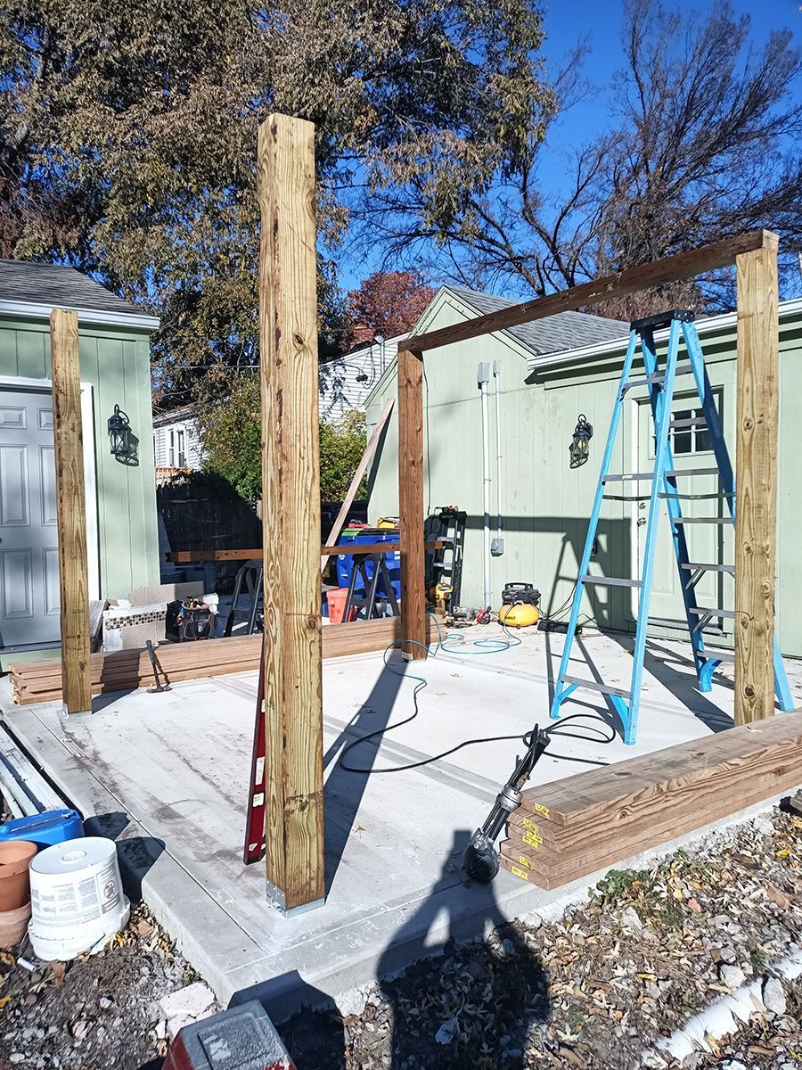 A wooden structure is being built on a concrete patio in front of a house.