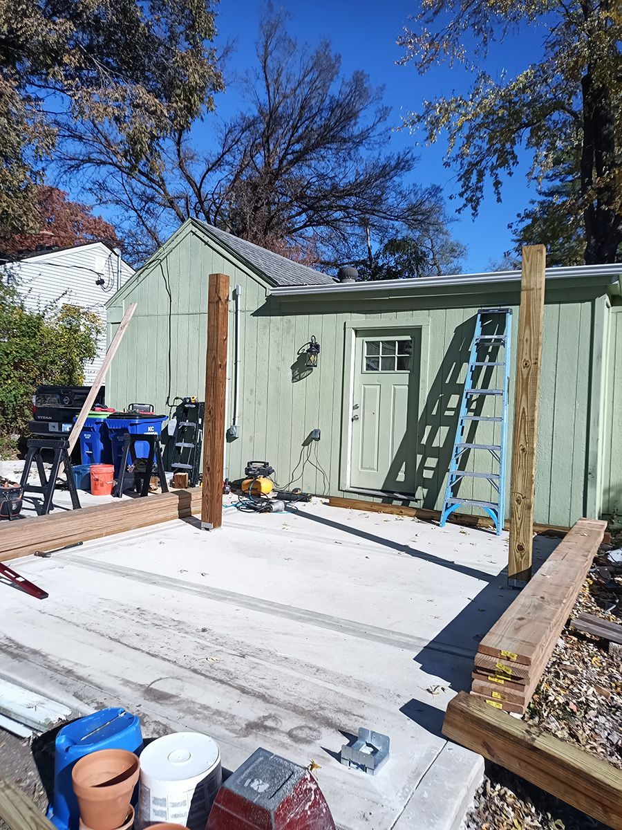 A green shed is being built with wooden posts and a ladder.