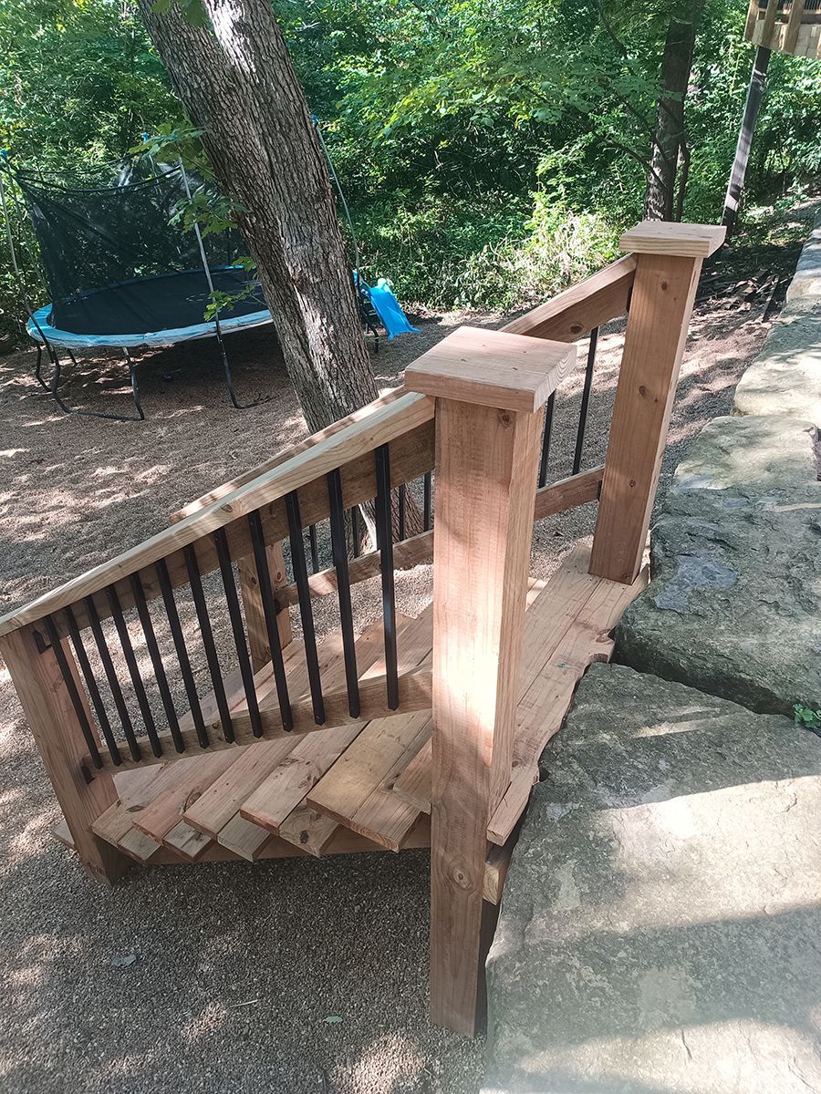 A wooden deck with stairs and a trampoline in the background.