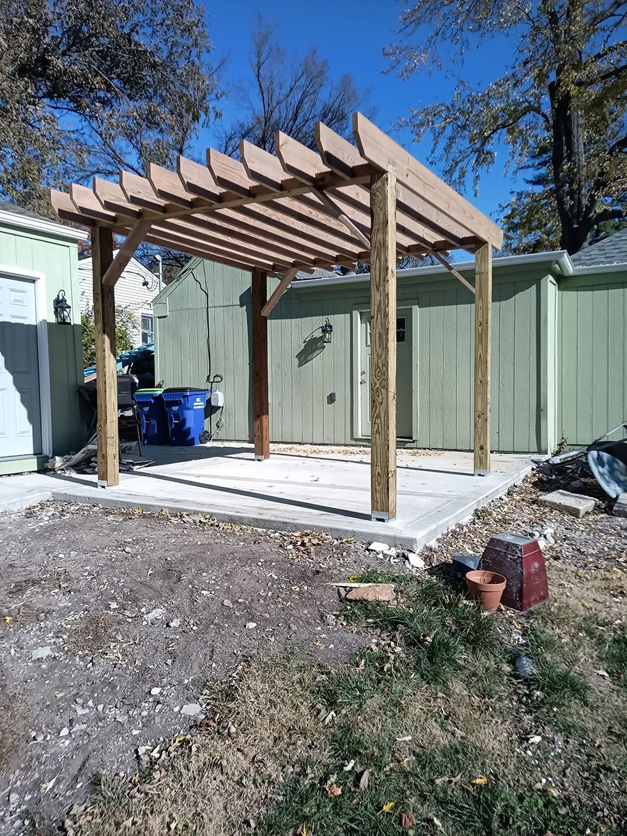 A wooden pergola is being built in the backyard of a house.