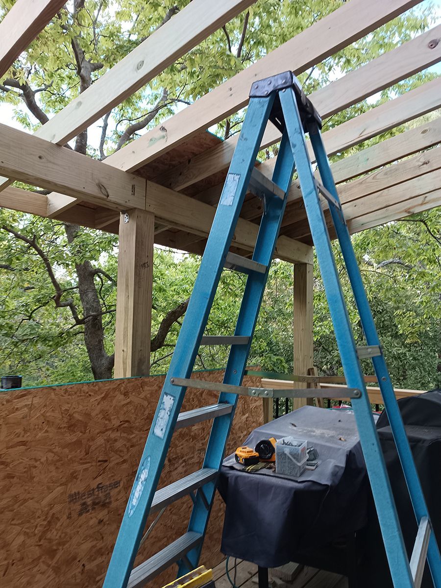 A blue ladder is sitting on top of a wooden structure.