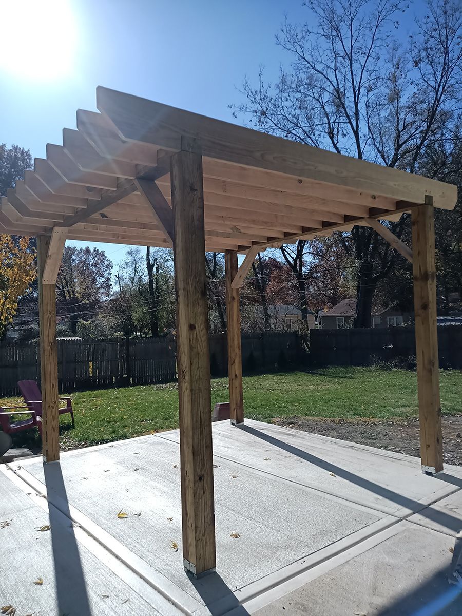 A wooden pergola is sitting on top of a concrete patio in a backyard.